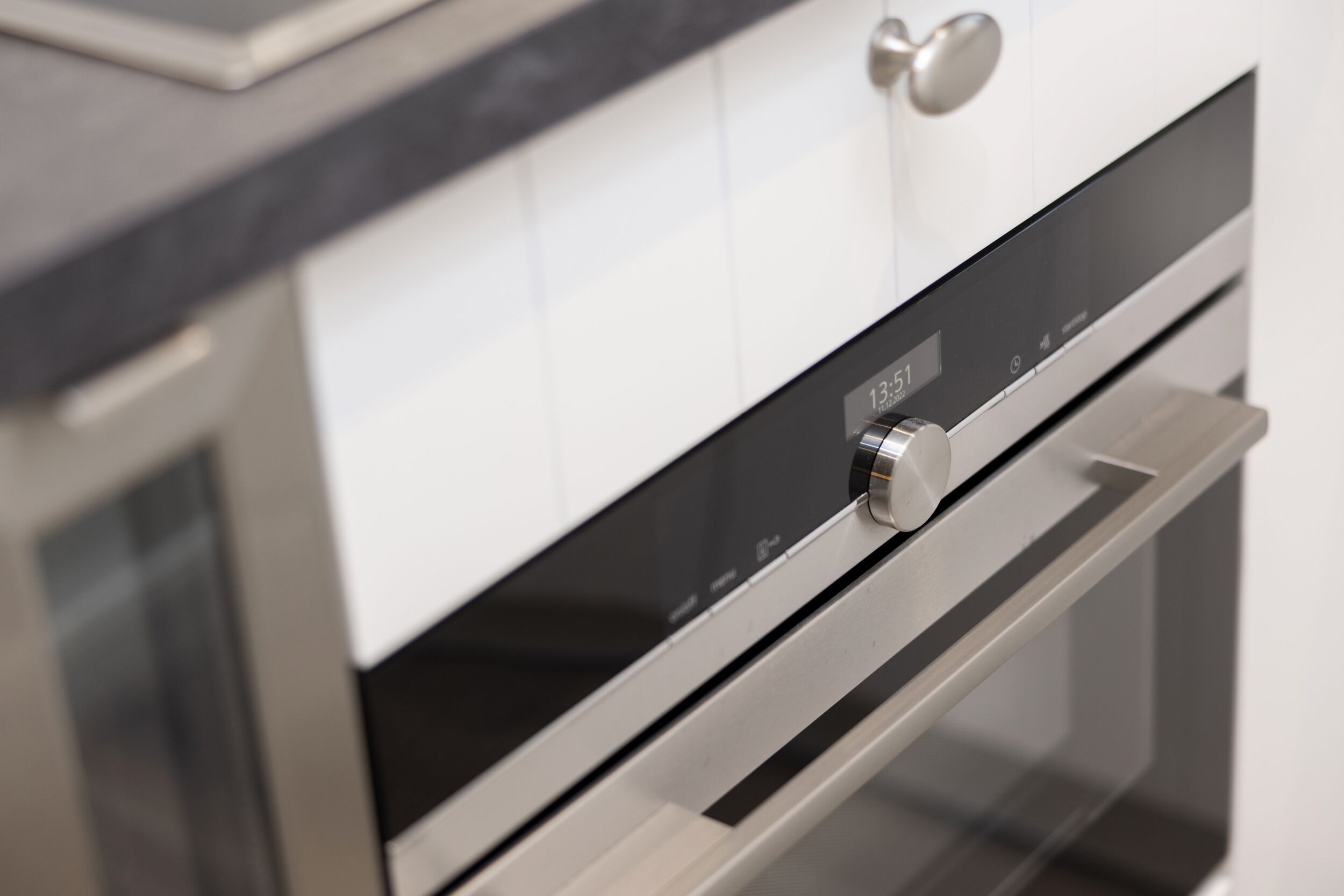 Una cocina moderna con electrodomésticos de acero inoxidable, un reloj digital y un diseño elegante.