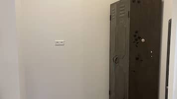 A small, dimly lit room with a wooden cabinet, a power outlet, and a coiled cable on the floor.