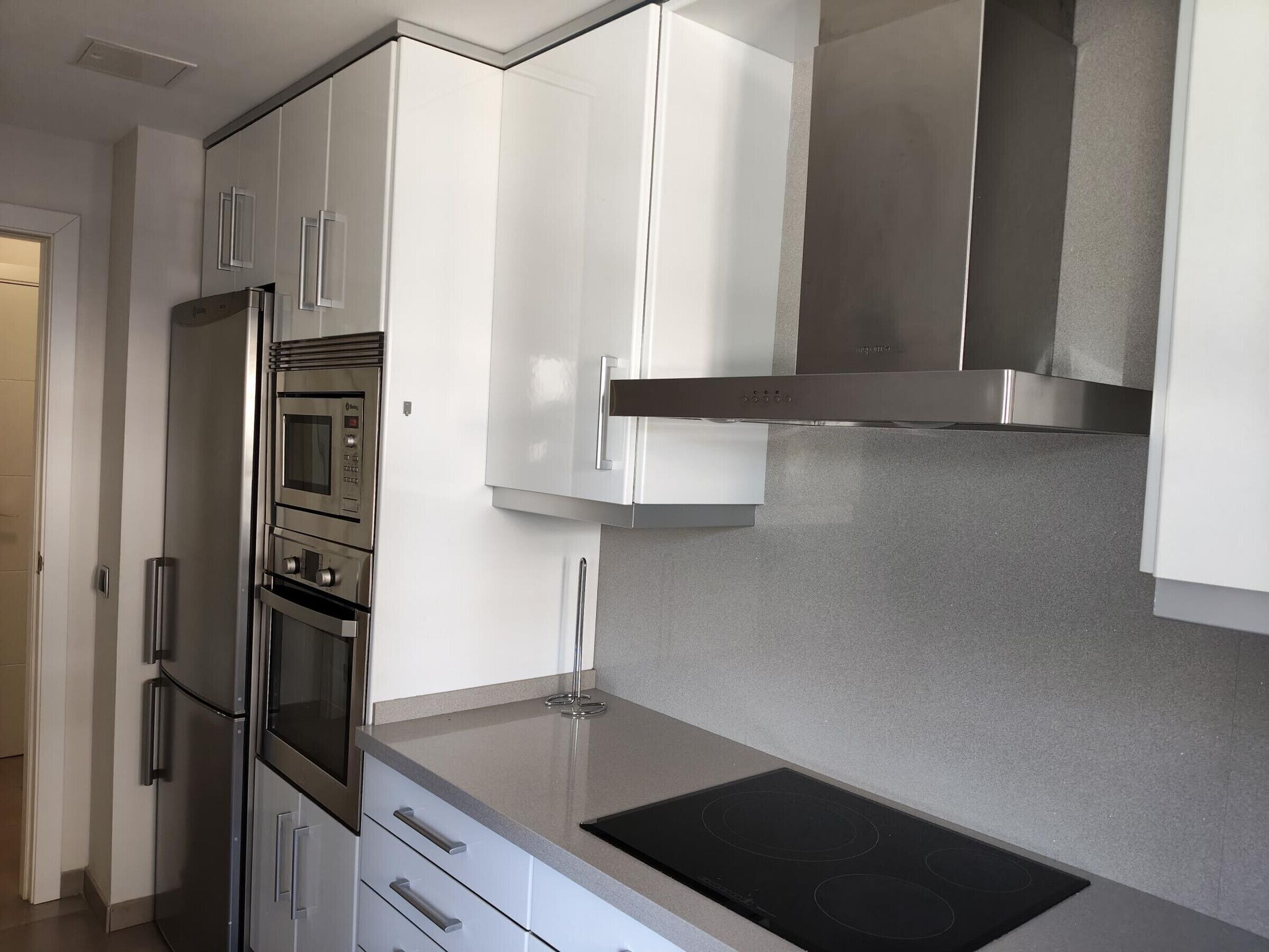 Een moderne keuken met roestvrijstalen apparatuur, witte kastjes en een ingebouwde kookplaat.