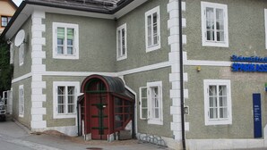 Un bâtiment à la façade verte, aux ornements blancs et à la porte rouge. Une enseigne indiquant « Steiermärkische Sparkasse » est visible sur le côté droit.