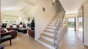 A spacious living area with a staircase, a sofa set, a coffee table, and a television. - Villa with Heated Pool, Tennis Court, Jacuzzi, Games Room, WIFI and AC  (Moncarapacho)