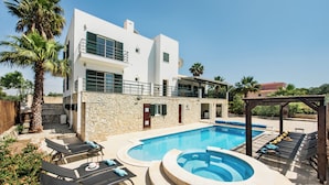A modern two-story building with a swimming pool, lounge chairs, and a stone wall. - Villa with Heated Pool, Tennis Court, Jacuzzi, Games Room, WIFI and AC  (Moncarapacho)