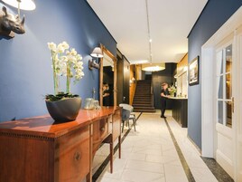 A hallway with a wooden console table, a large mirror, and a staircase leading to another room.