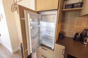 A kitchen with a built-in refrigerator, wooden cabinets, and a tiled backsplash. - Top location! Next to lighthouse, beach 50m FLOW (Egmond aan Zee)