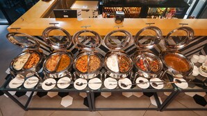 Un bufé con diversas opciones de comida y un área de bar al fondo.