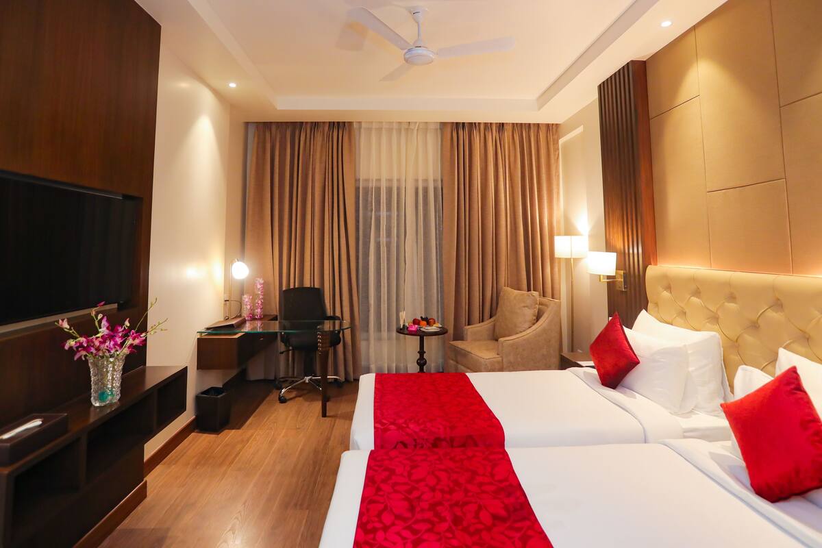 Une chambre d’hôtel équipée d’un lit, d’un bureau, d’une chaise, d’une télévision et d’un ventilateur de plafond.