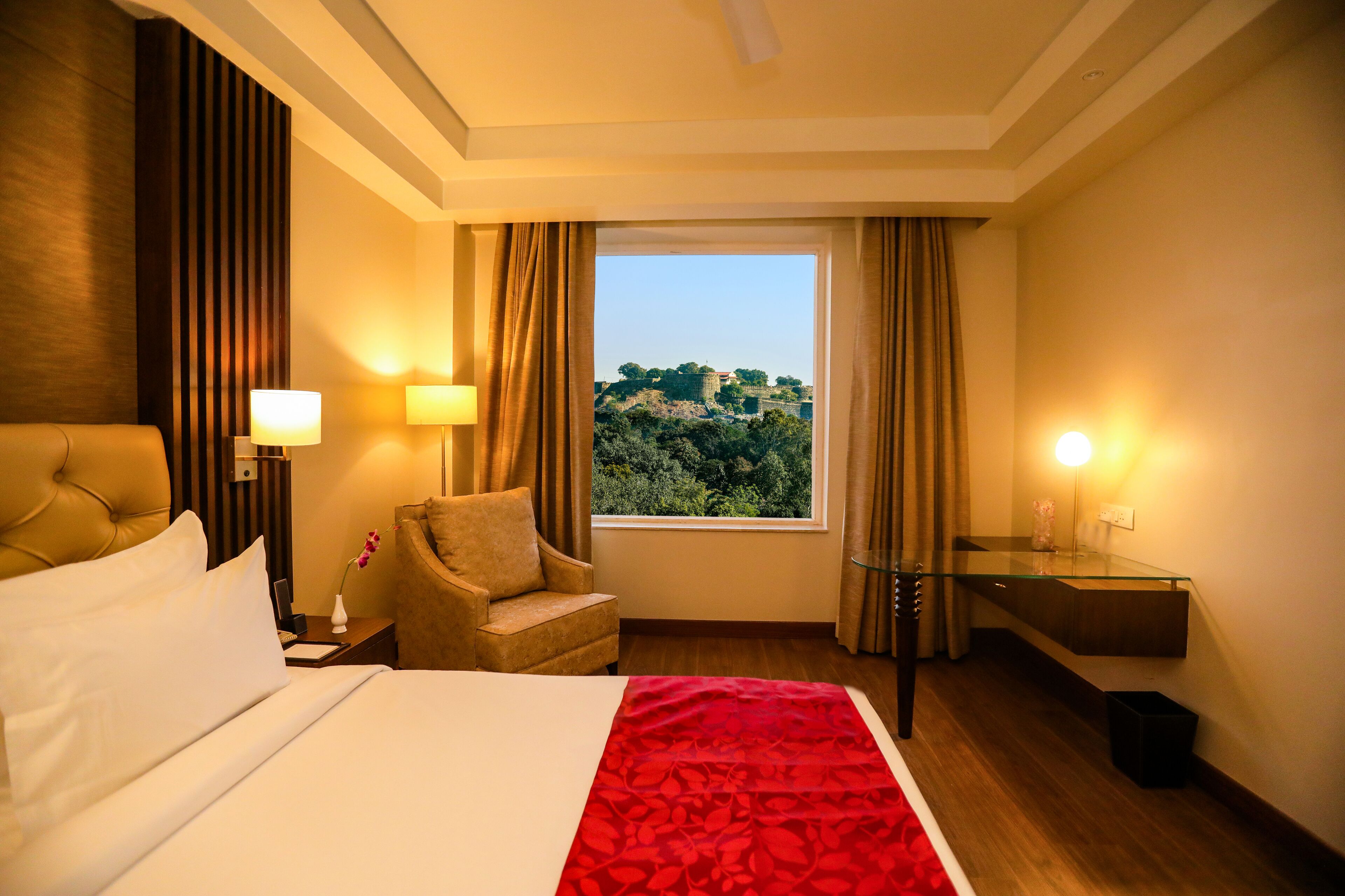 Una habitación de hotel con cama, una silla, un escritorio y vistas a una colina.
