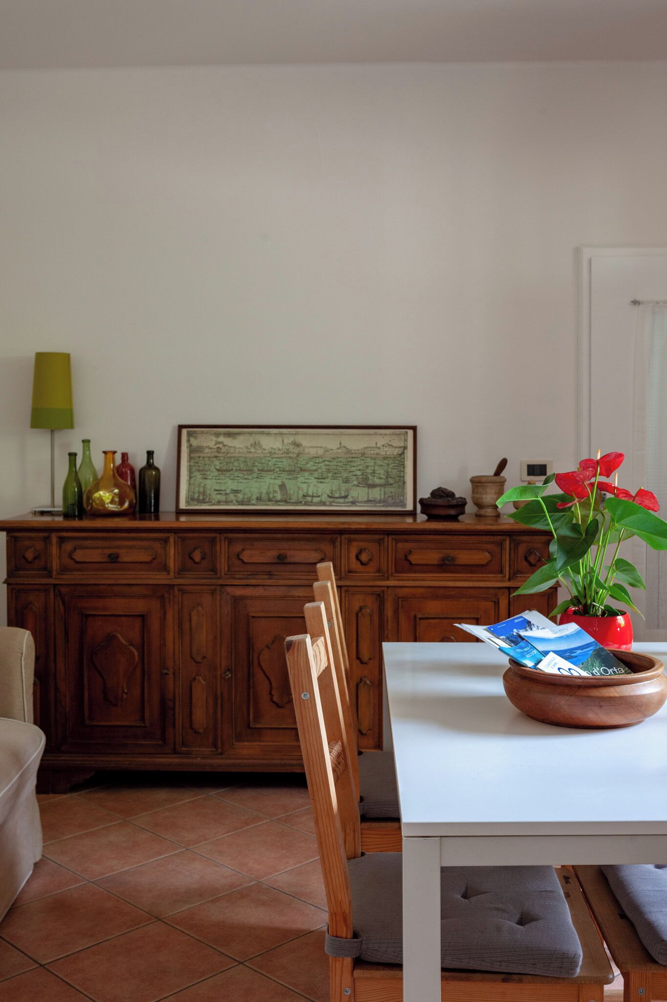 Un coin repas comprenant un buffet en bois, une table avec une seule chaise et une plante en pot.