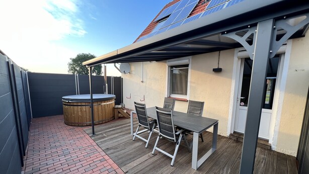 A covered patio with a hot tub, a table, and chairs. - Beautiful holiday home with hot tub. In short: relax and enjoy! (Neubörger)