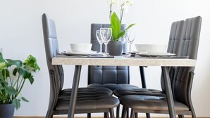 A dining table with four chairs, a potted plant, and a vase of white flowers. - Beautiful holiday home with hot tub. In short: relax and enjoy! (Neubörger)