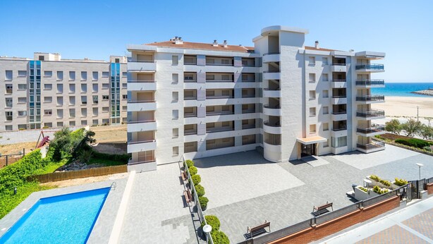 Un hotel de varios pisos con piscina en la azotea y vista al mar.
