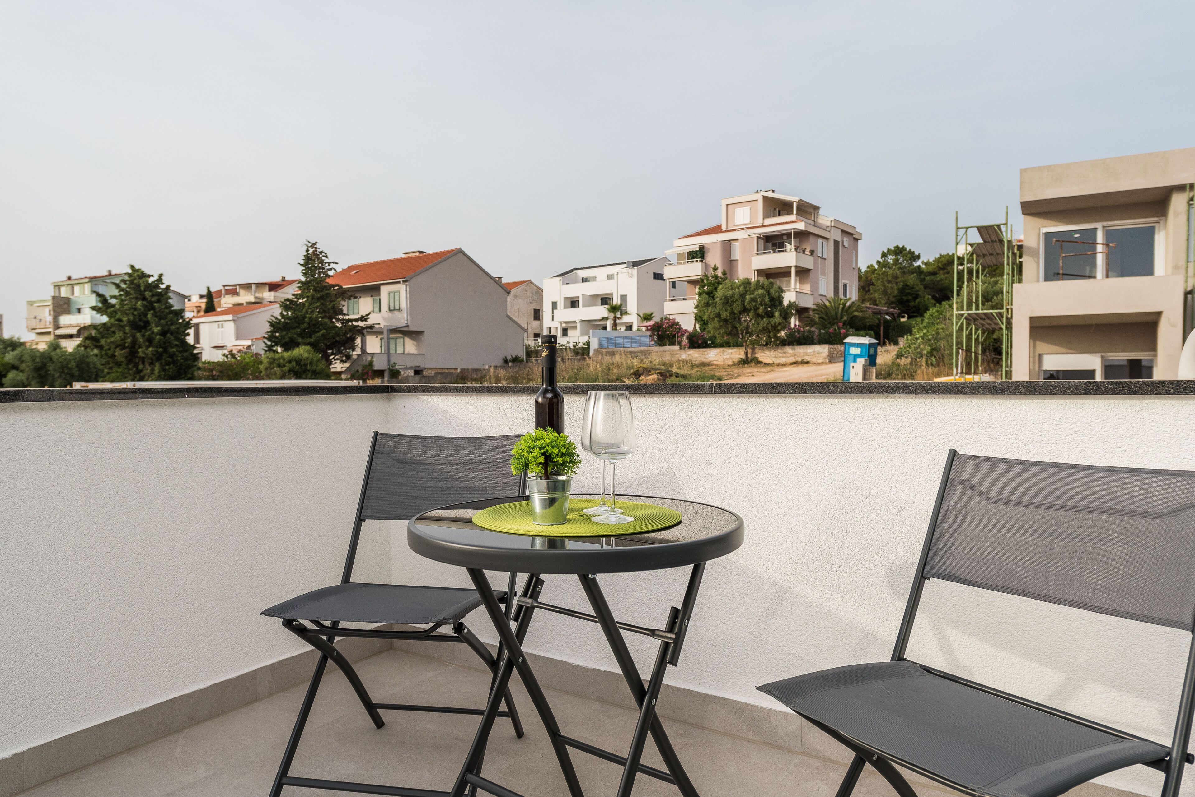 A balcony with two chairs, a small table, and a potted plant.