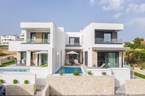 Una casa moderna de dos pisos con piscina, mobiliario exterior y fachada de piedra.