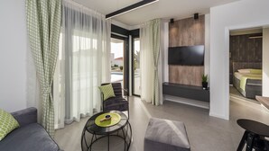 En moderne stue med sofa, rundt bord med bakke og et TV ophængt på væggen.