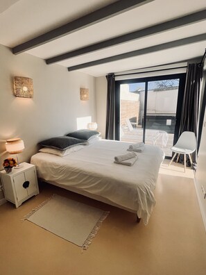 Ein modernes Schlafzimmer mit einem großen Bett, Nachttischlampen, einem kleinen Schrank und Blick ins Freie.