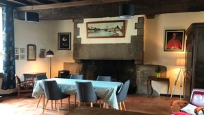 A dining area with a stone fireplace, a table with chairs, and a wooden bench.