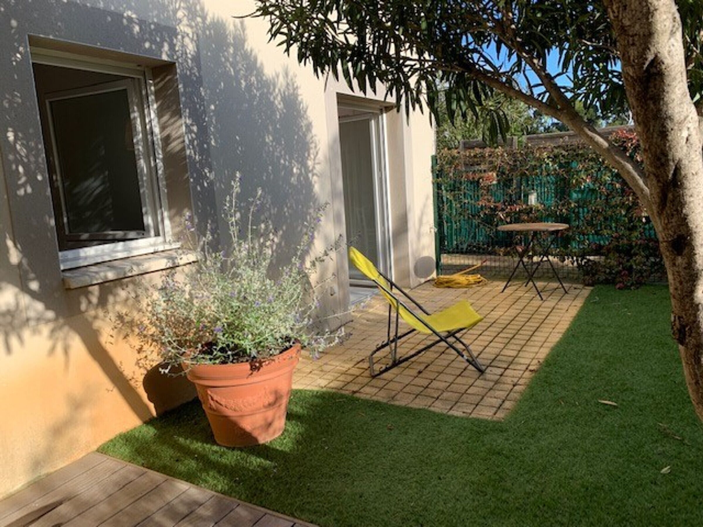 Een terras met een bloempot, een gele stoel en een klein tafeltje.