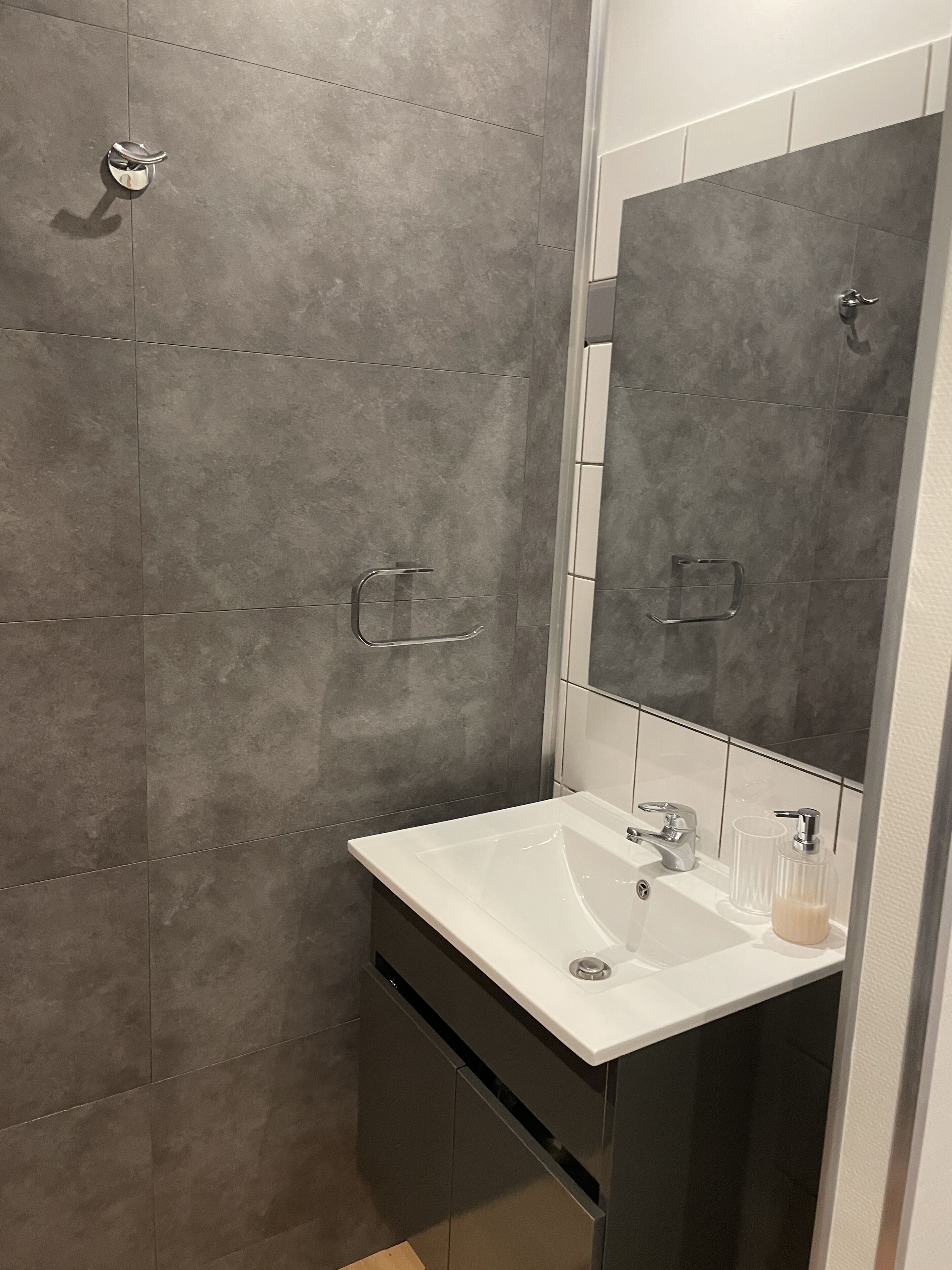 Un baño con lavamanos blanco, un espejo y una ducha.