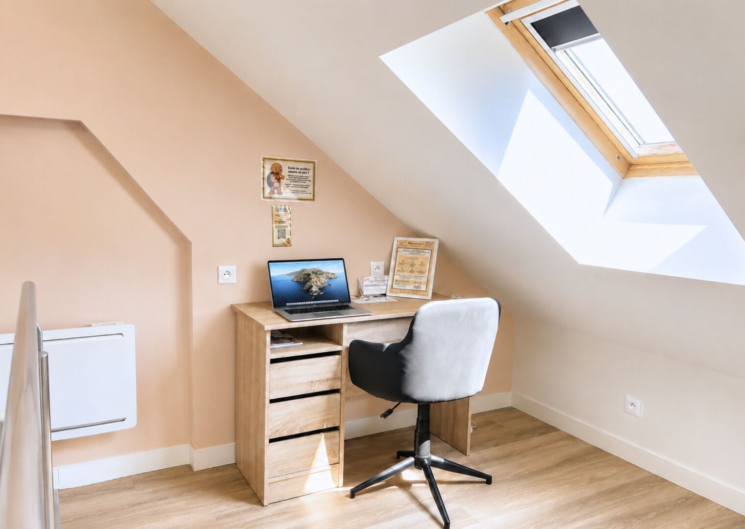 A small office space with a desk, chair, and a skylight.