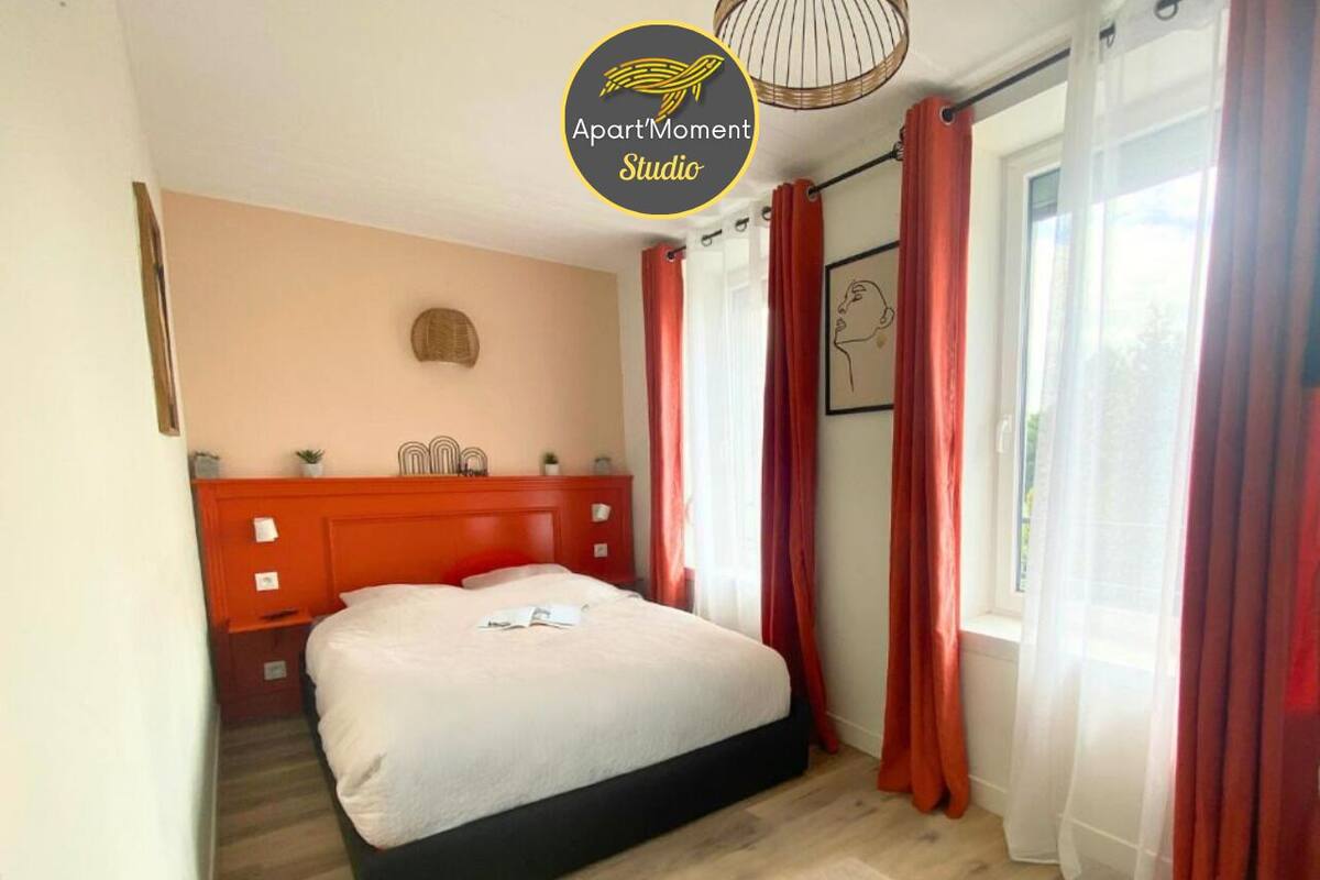 Un dormitorio con cama, cabecera de madera, ventana con cortinas rojas y una obra de arte colgada en la pared.