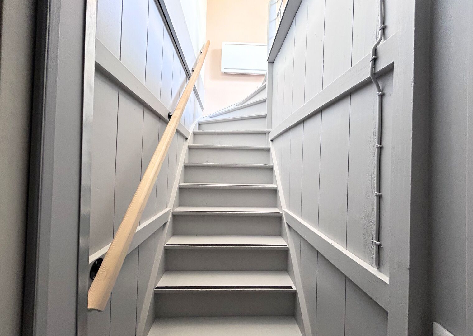 Un escalier avec des rampes en bois et un mur de couleur claire.