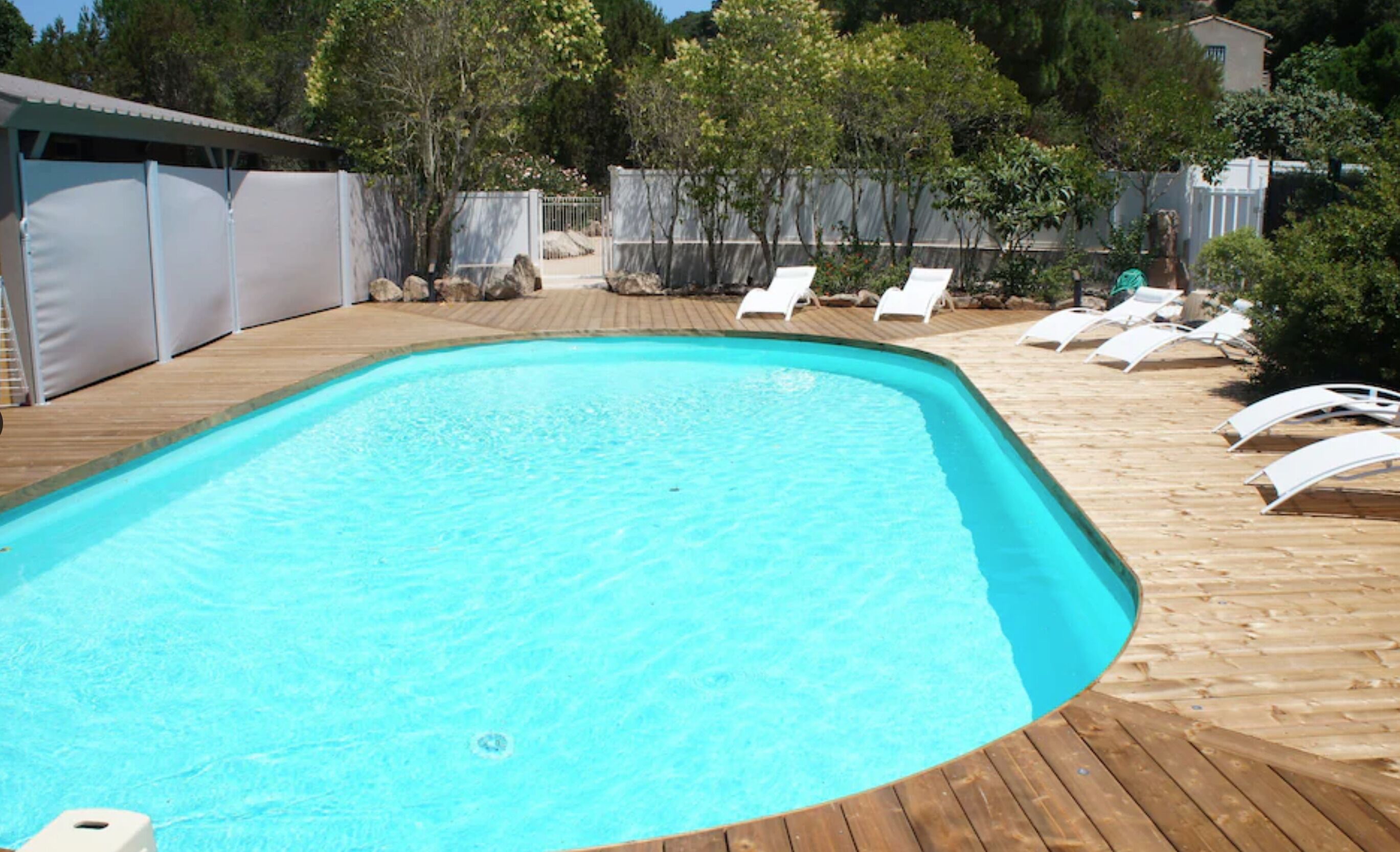 A rectangular swimming pool with a wooden deck surrounding it.