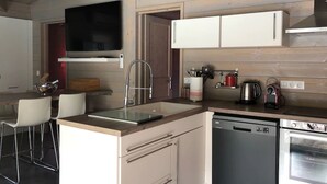 Una cocina moderna con lavavajillas, horno y televisor de pantalla plana montado sobre la encimera.