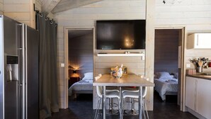 Cocina compacta con una isla central, un refrigerador y un comedor con sillas.