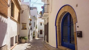 Una estrecha calle adoquinada bordeada por edificios blancos con puertas y ventanas azules.