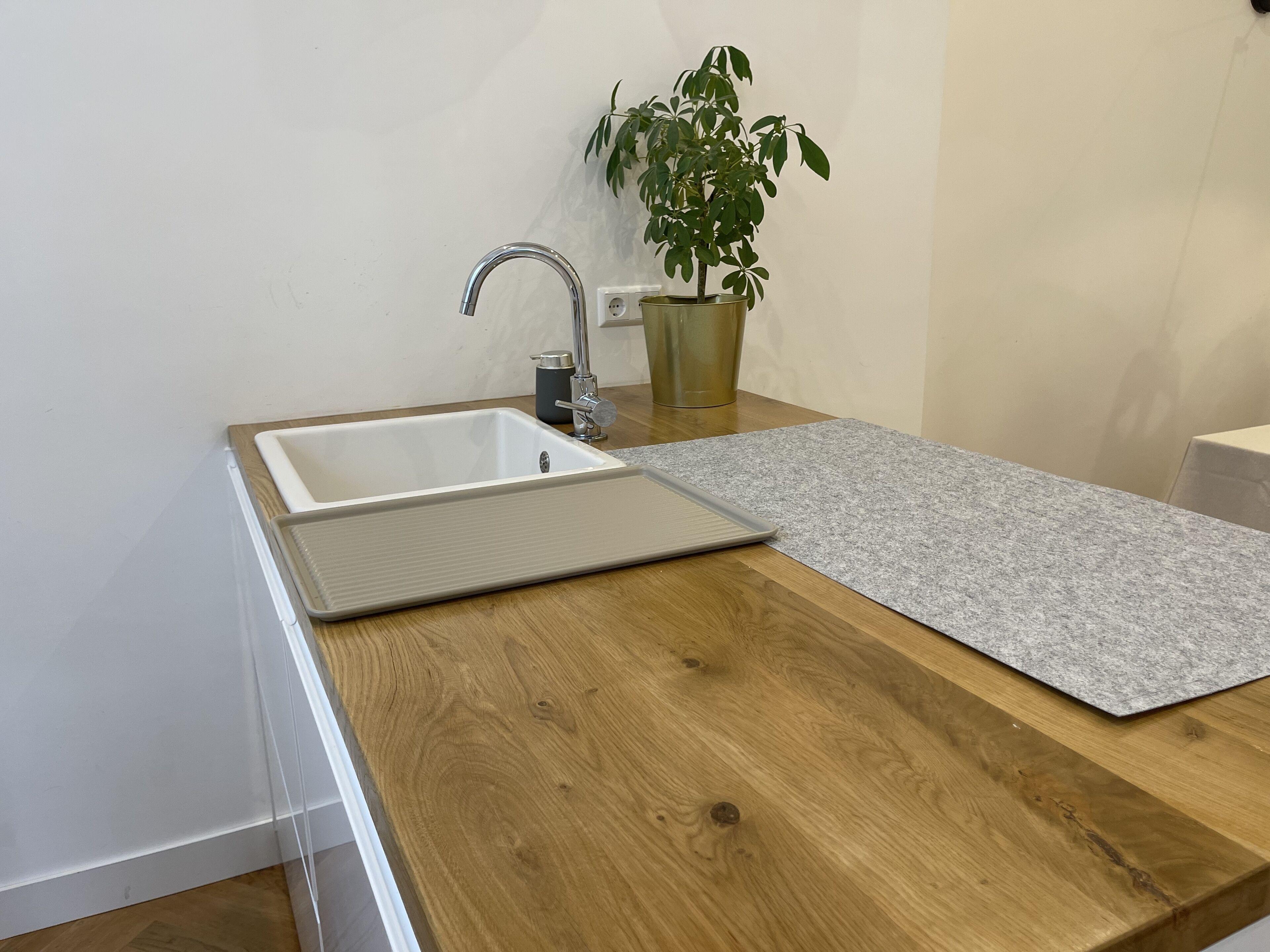 Une cuisine avec un évier blanc, un plan de travail en bois et une plante en pot.