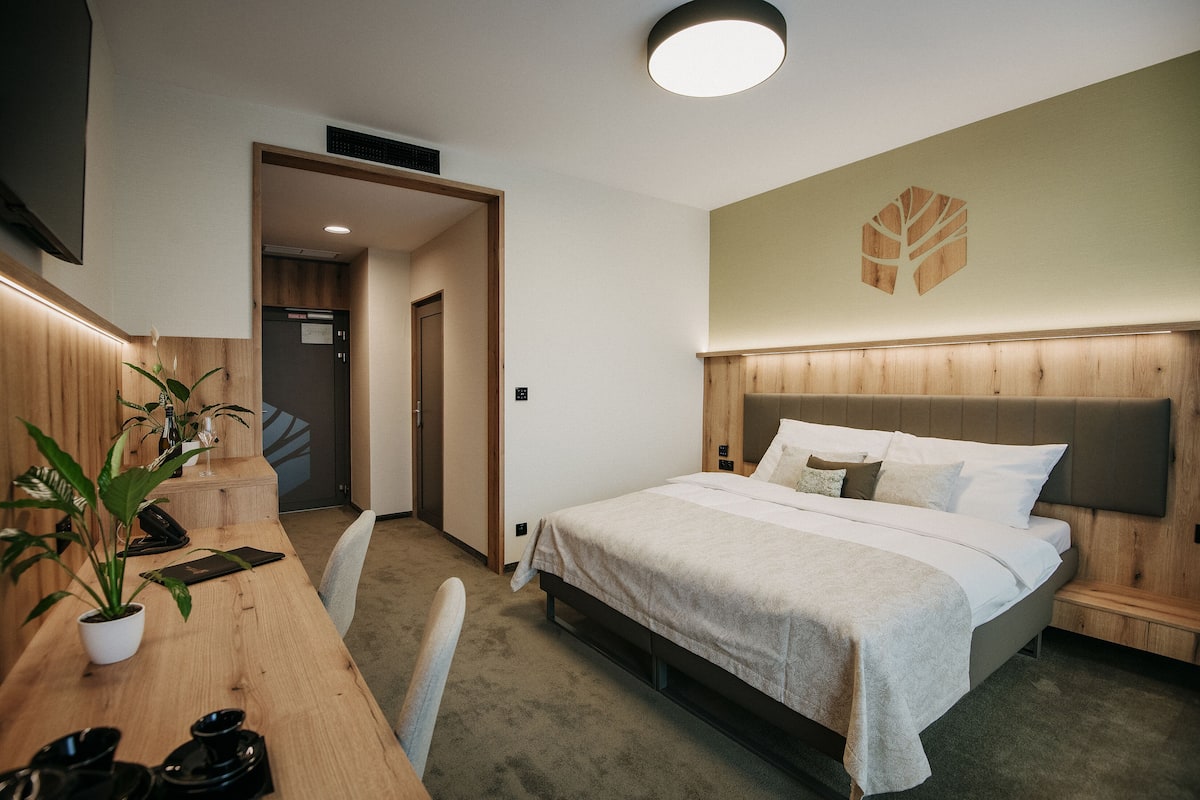 Una habitación de hotel con cama, mesita de noche y una planta en maceta.