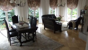 Un salon spacieux avec un coin repas, comprenant une grande fenêtre, un canapé, une table basse et une cheminée.