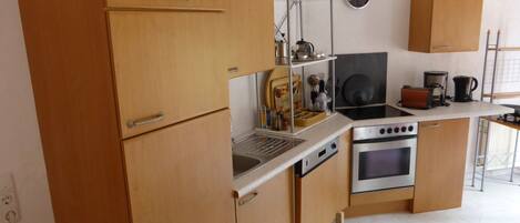 Una cocina compacta con armarios de madera, estufa, horno y cafetera.