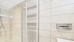 A modern bathroom with a glass shower enclosure, a white towel rack, and a sink with a chrome faucet. - Luxurious 2-Bedroom Apartment in New Residence, Sleeps 6 – Heart of Les Gets (Les Gets)