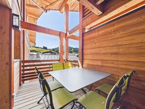 Een houten interieur met een tafel en stoelen, een uitzicht op een bergachtig landschap en een houten plafondconstructie.