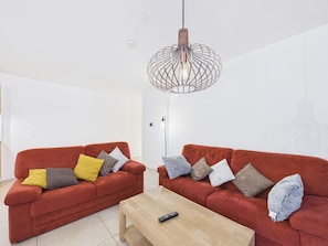 A modern living room with two red sofas, a wooden coffee table, and a unique spherical pendant light.