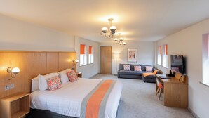 A modern hotel room with a large bed, a desk, a sofa, and a TV. - Park Head Hotel (Bishop Auckland)