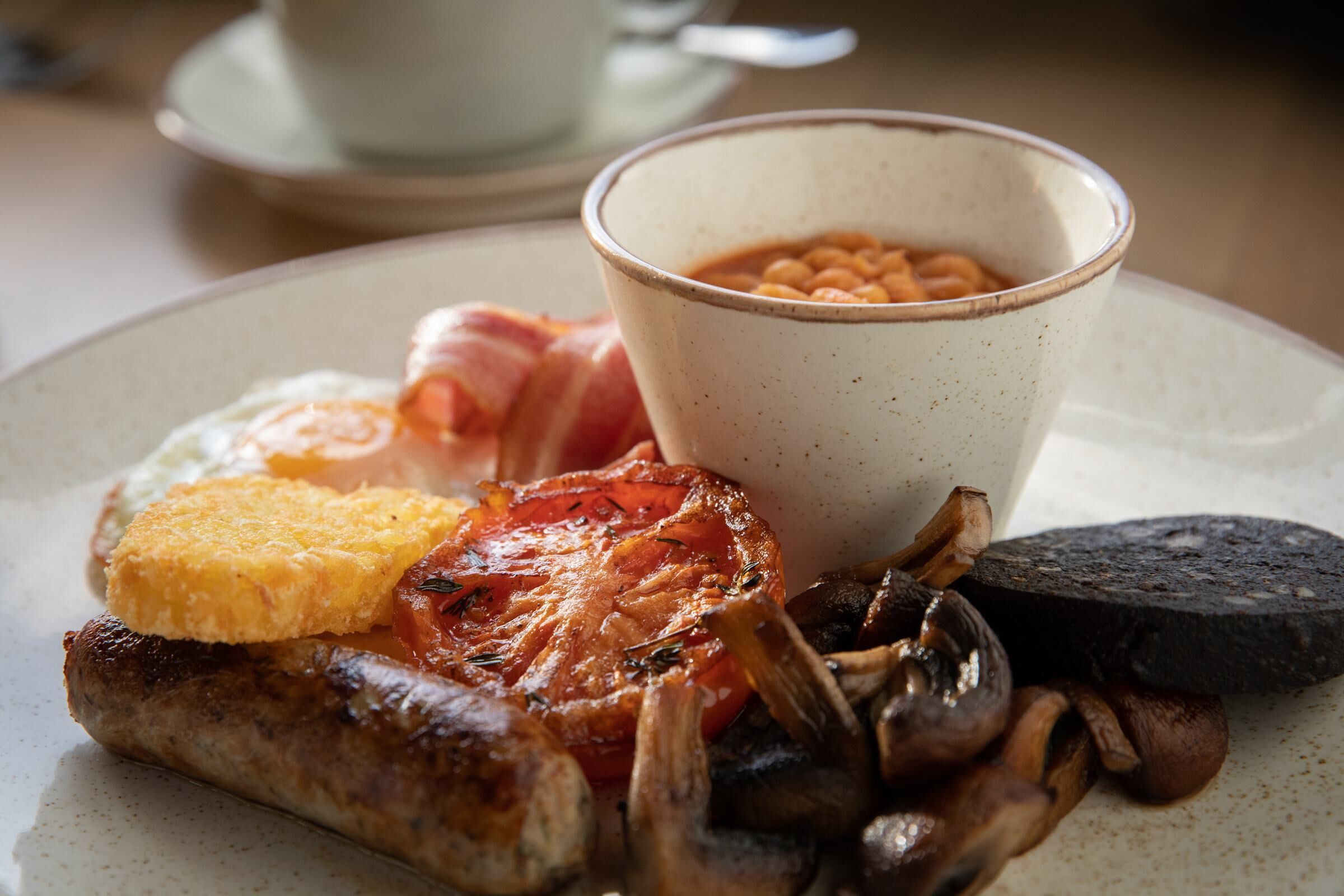 A plate of breakfast food including eggs, bacon, mushrooms, and beans.