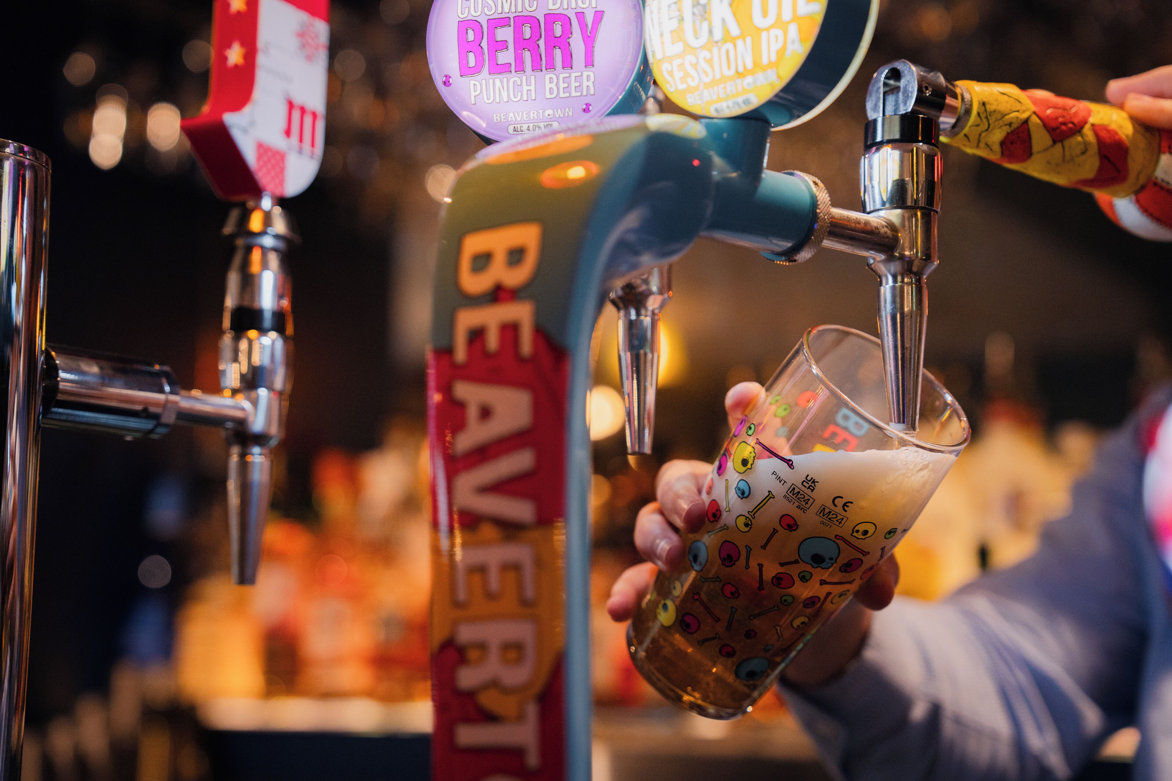A hand pouring beer from a tap labeled "BEAVER" into a glass.