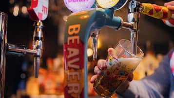 A hand pouring beer from a tap labeled "BEAVER" into a glass.