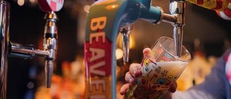 A hand pouring beer from a tap labeled "BEAVER" into a glass.