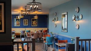 A restaurant with wooden tables and chairs, blue walls, and decorative plates on the wall. - Park Head Hotel (Bishop Auckland)