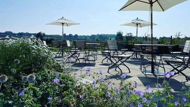 An outdoor seating area with tables and chairs, each with a large umbrella. - Park Head Hotel (Bishop Auckland)