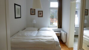 A bedroom with a bed, a window, a radiator, and framed pictures on the wall. - Welcome to the harbor district - Emma (Wismar)