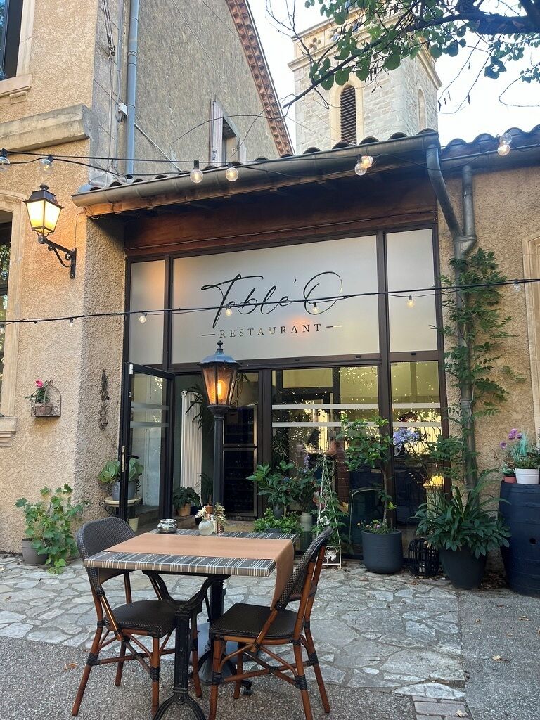 A restaurant with outdoor seating, a stone facade, and a sign that reads 'Table Café Restaurant.'