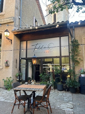 A restaurant with outdoor seating, a stone facade, and a sign that reads 'Table Café Restaurant.'