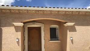 Una entrada de edificio con puerta de madera, ventana arqueada y un pequeño balcón.