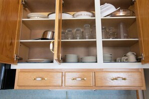 A kitchen with wooden cabinets, glassware, and dishes.