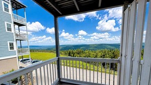 Een balkon met uitzicht op een groen landschap en verre bergen.
