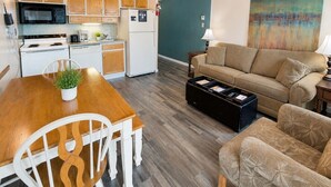 Een knus woongedeelte met een kitchenette, een eettafel met stoelen, een bank en een salontafel.
